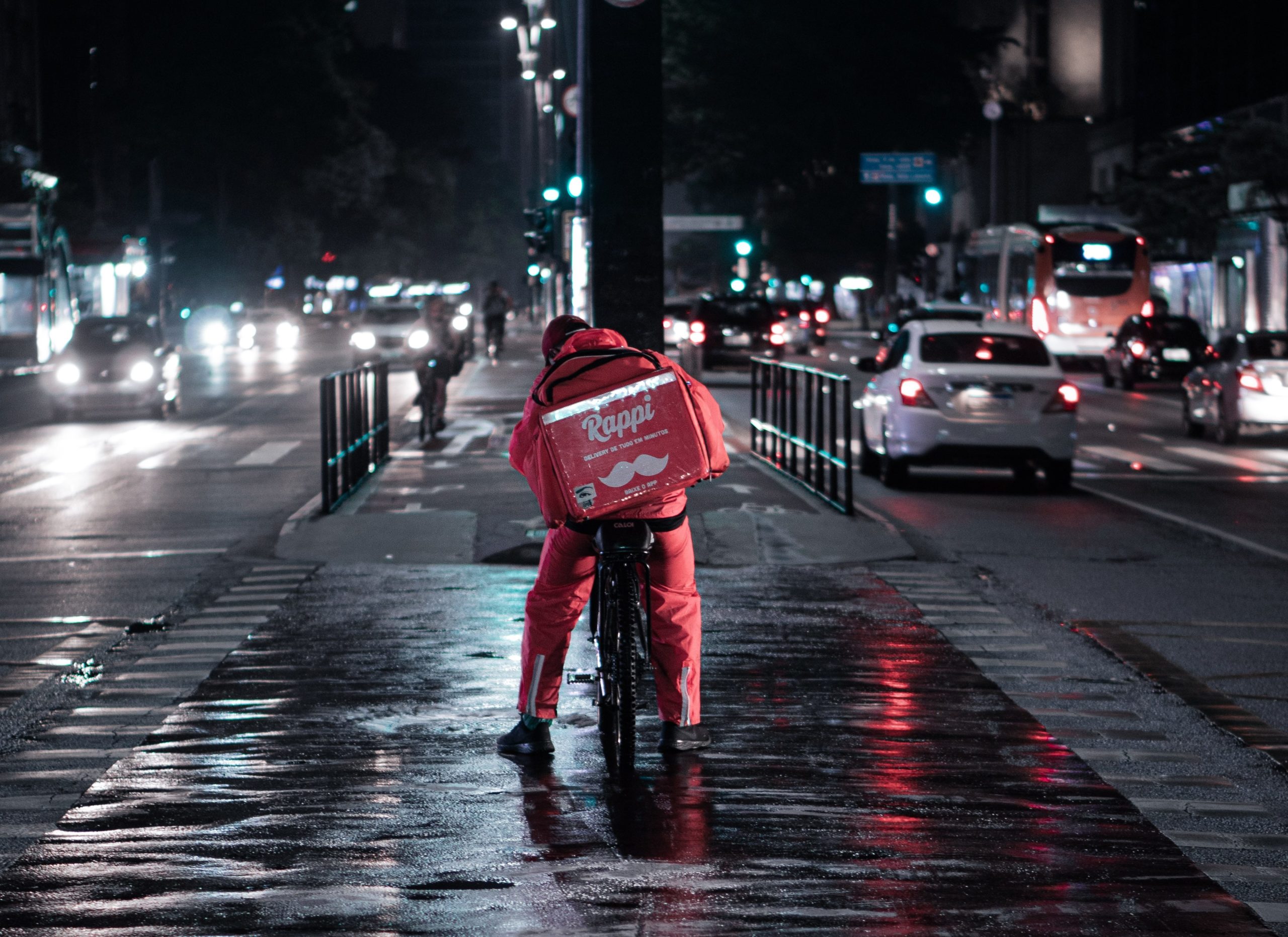 person in red jacket and blue denim jeans walking on street during night time